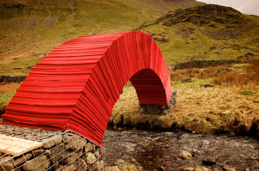 Красочный мост из бумаги с опорой из камня в сварных габионах